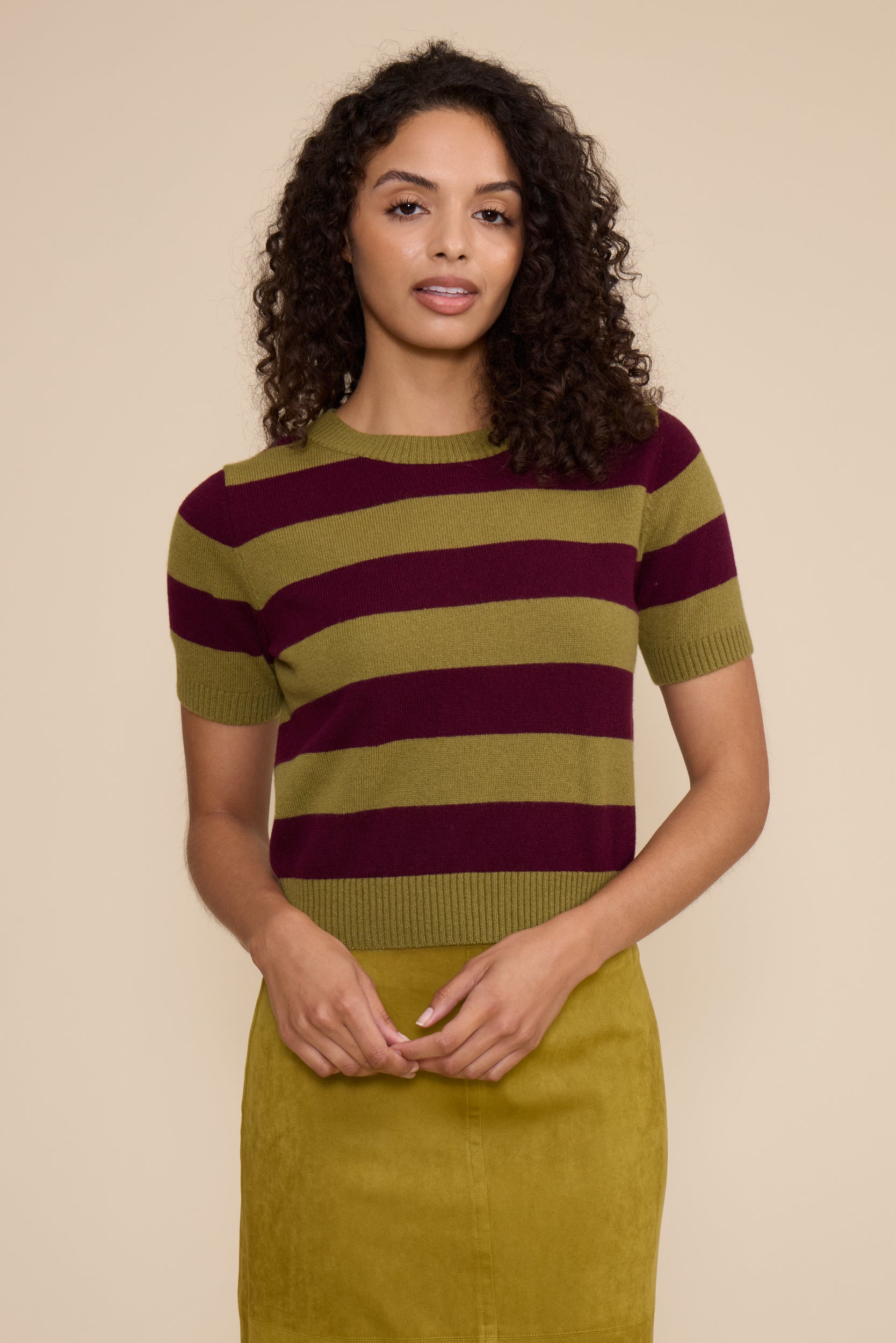 Woman wearing a striped sweater and skirt against a beige background
