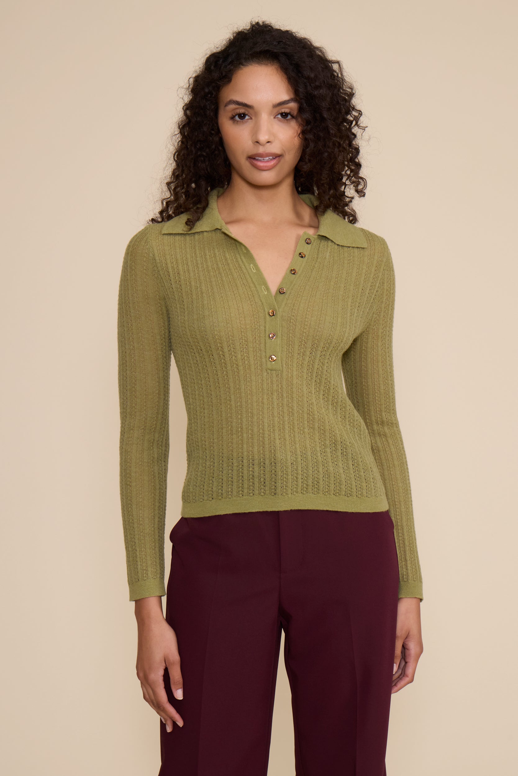 Woman wearing a green ribbed sweater with a beige background