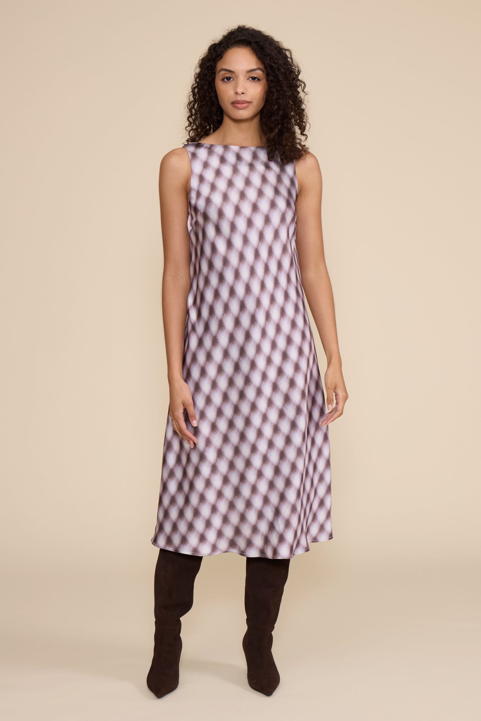 Woman wearing a sleeveless checkered dress on a beige background